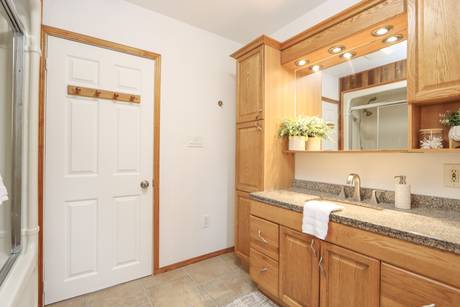 Bathroom with a wide wooden vanity, mirror and light walls