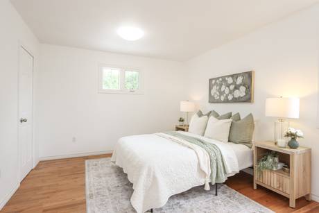 Bedroom with white bedding, a grey rug and light floors