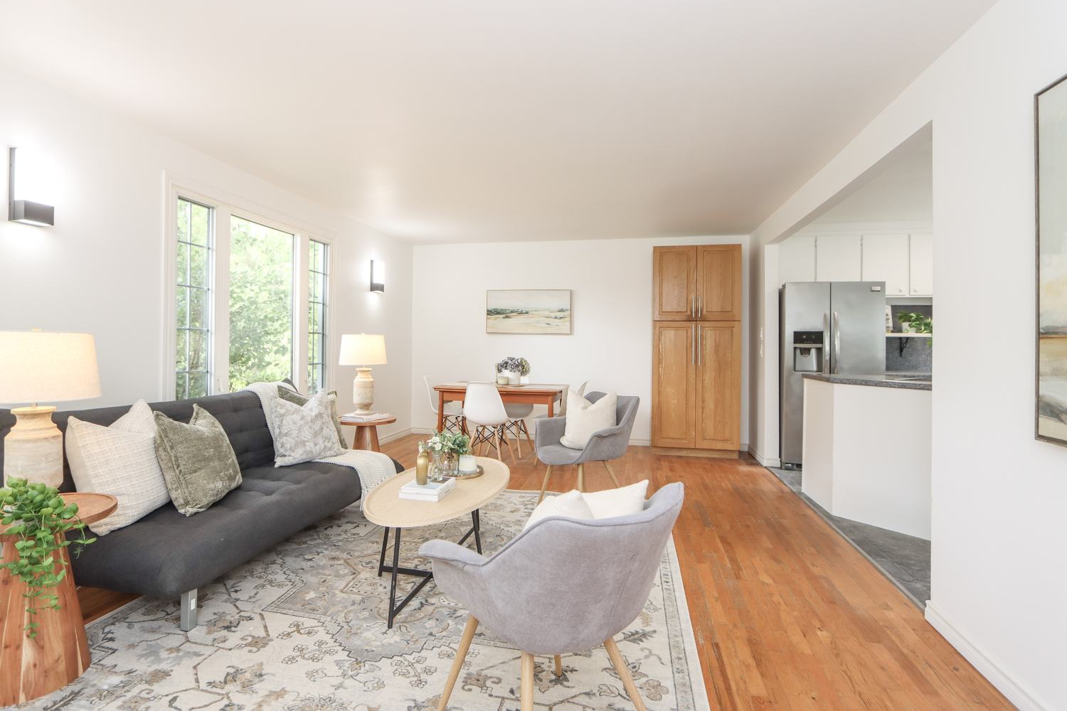 Bright living room with hardwood floors, a grey sofa and armchairs